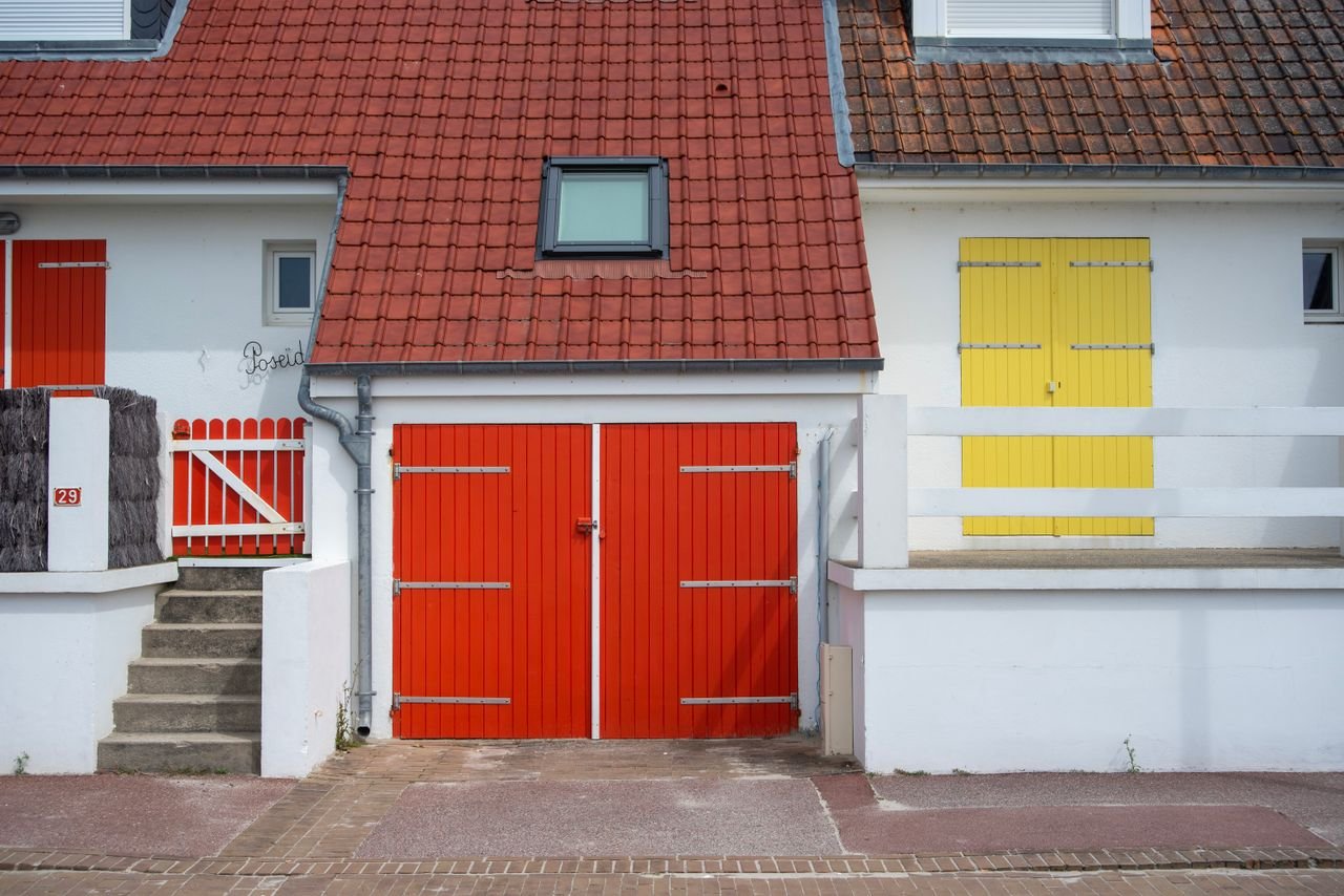 Brightly colored house facade featuring red and yellow doors and a red tiled roof.
